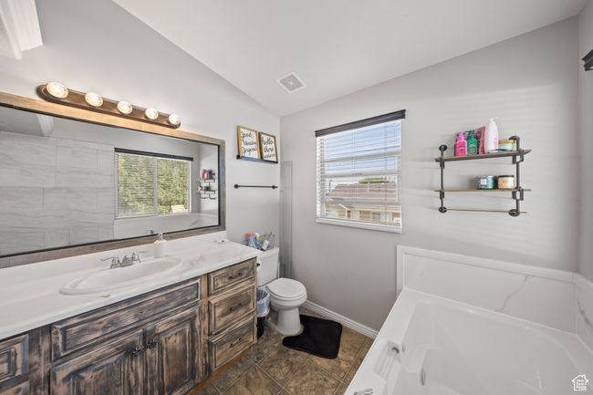 master bathroom featuring vaulted ceiling, a garden tub, and vanity | Image 14