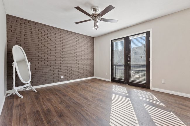 Unfurnished room featuring ceiling fan, wood finished floors, brick wall, and baseboards | Image 14