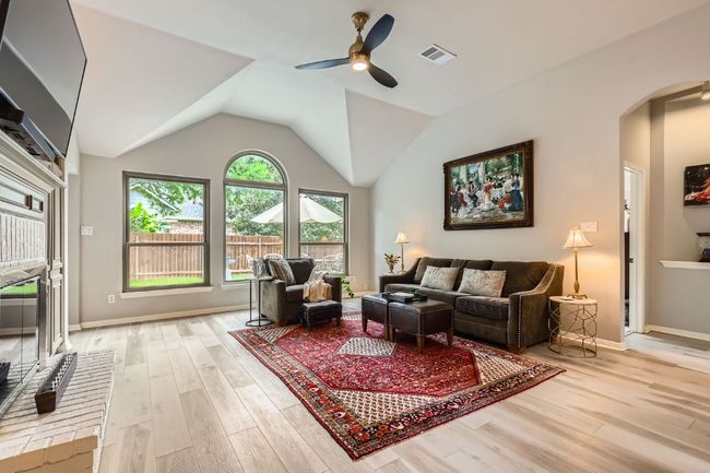 Living area with arched walkways, a ceiling fan, light wood-style floors, and lofted ceiling | Image 22