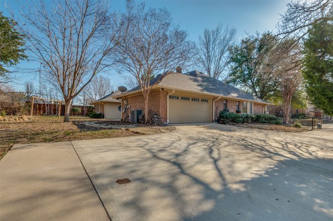 View of front of property featuring brick siding, central AC unit, fence, a garage, and driveway | Image 32
