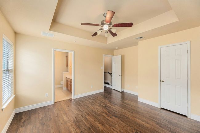 Unfurnished bedroom with a tray ceiling, multiple windows, dark wood finished floors, and ensuite bath | Image 15