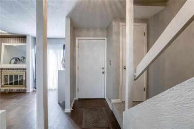 Foyer featuring a textured ceiling, a fireplace, and wood-type flooring | Image 3