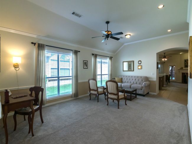 Large open Living/Dining Room combination showcases crown molding, elevated ceiling, and arched opening to kitchen and casual living area. | Image 6