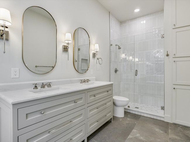 Bathroom featuring double vanity, a stall shower, a sink, and toilet | Image 12