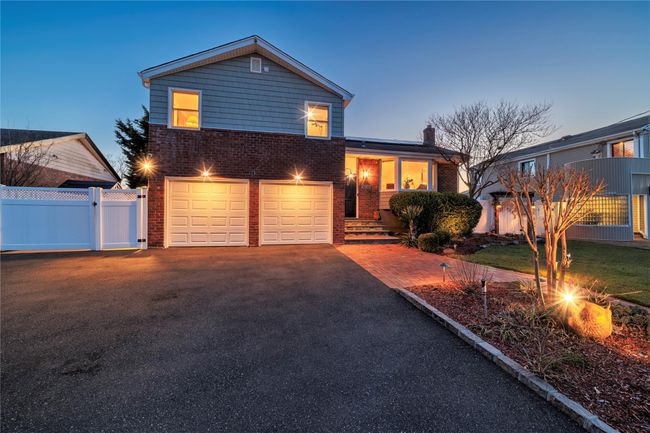Tri-level home with aphalt driveway, a gate, fence, an attached garage, and brick siding | Image 42