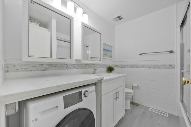 Full bath featuring toilet, visible vents, vanity, and washer / dryer | Image 7