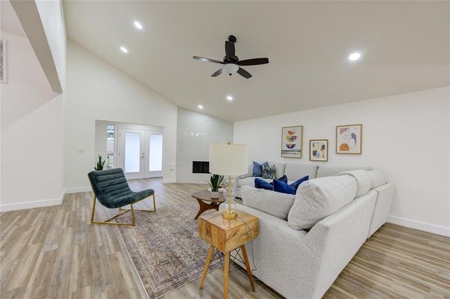 The spacious living room is the heart of this home, offering an abundance of natural light thanks to the large new windows. The room features an updated modern fireplace, adding both warmth and style to the space. The sleek, minimalist design of the fireplace complements the home’s contemporary vibe, making it a perfect focal point for gatherings. | Image 7