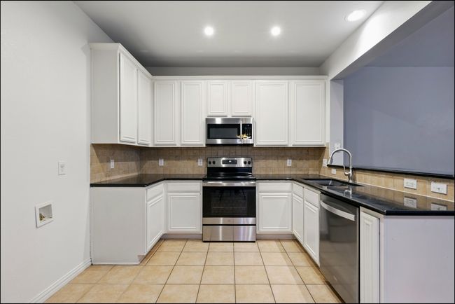 Kitchen featuring stainless steel appliances, white cabinetry, a sink, and tasteful backsplash | Image 11