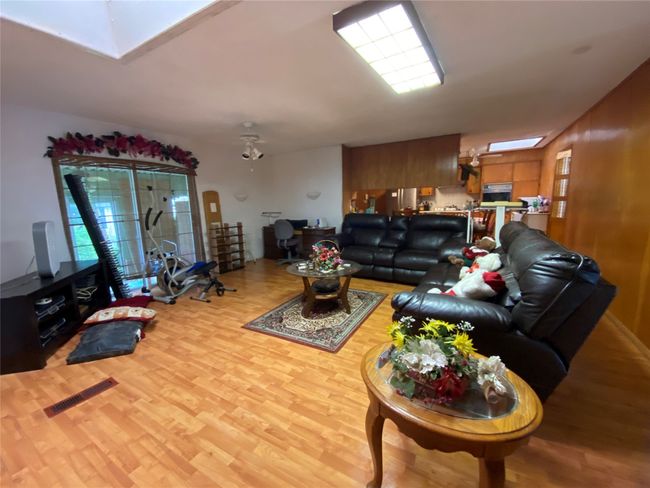 Living room with a skylight and wood finished floors | Image 5