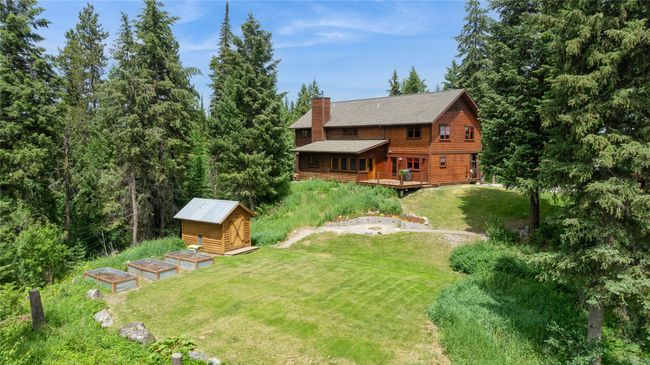 View of grassy yard with sauna, a deck, and a garden | Image 7