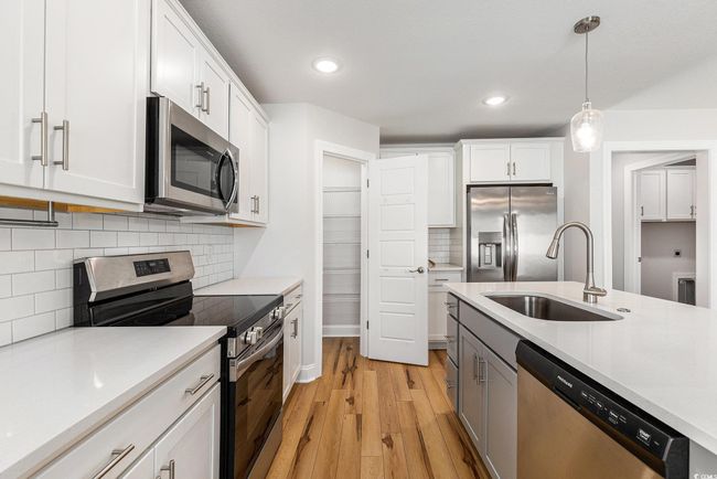 Kitchen featuring appliances with stainless steel finishes, light wood-type flooring, light countertops, and recessed lighting | Image 11