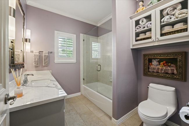 Bathroom featuring baseboards, toilet, vanity, ornamental molding, and combined bath / shower with glass door | Image 19