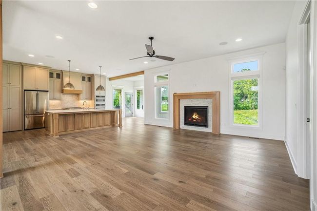 Unfurnished living room featuring wood finished floors, a lit fireplace, recessed lighting, ceiling fan, and baseboards | Image 10