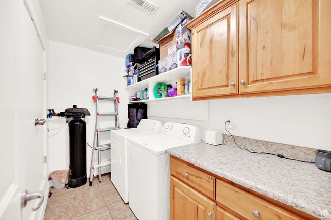 Laundry area featuring independent washer and dryer, cabinet space, attic access, and light tile patterned floors | Image 14