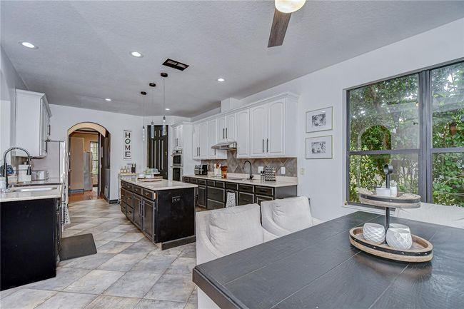 This beautifully updated kitchen features white 42” upper cabinets with crown and sleek black base cabinets! | Image 9