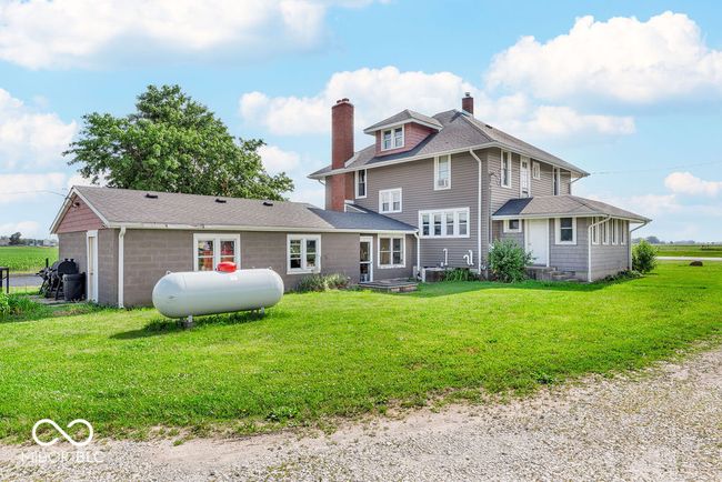 rear view of house featuring a chimney, a lawn, and a shingled roof | Image 11