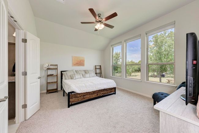 A 'wall' of windows and high ceiling enhance this spacious owner's bedroom. There's plenty of room to accommodate almost any furniture arrangement with a seating area. | Image 24