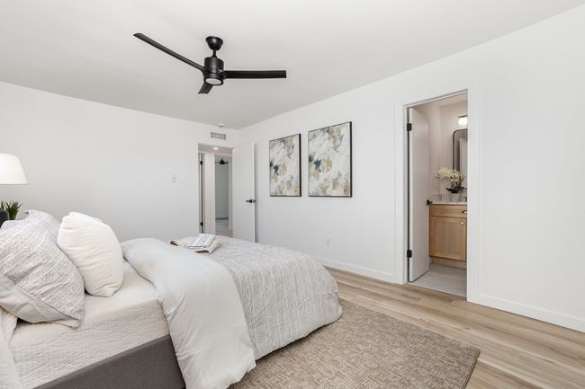 Bedroom with light wood-type flooring, ensuite bath, a ceiling fan, visible vents, and baseboards | Image 23