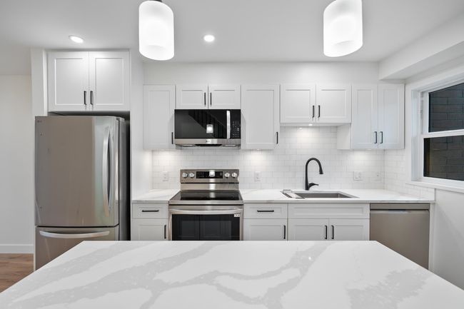 Kitchen featuring a sink, white cabinets, tasteful backsplash, and stainless steel appliances | Image 5