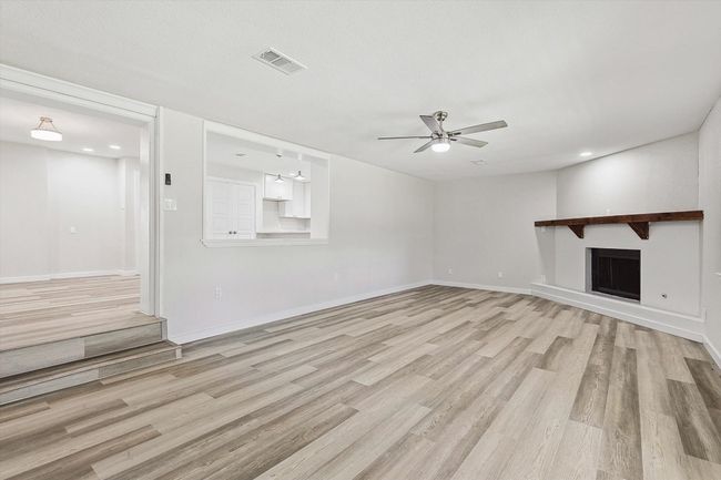 Unfurnished living room featuring a fireplace, ceiling fan, light wood-type flooring, visible vents, and baseboards | Image 22