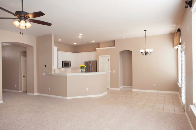 Unfurnished living room featuring arched walkways, light carpet, a chandelier, ceiling fan, and recessed lighting | Image 7