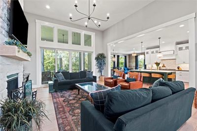 Living room with light wood-type flooring, sink, a stone fireplace, and a chandelier | Image 2