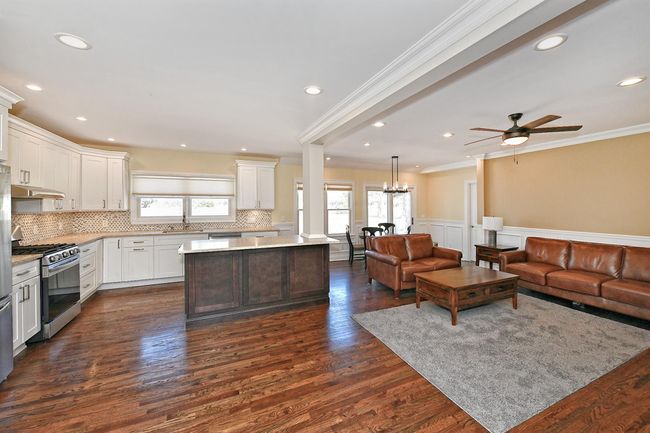 Kitchen featuring a healthy amount of sunlight, open floor plan, stainless steel gas range oven, and a sink | Image 13