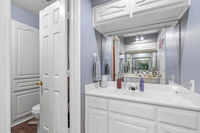 Bathroom with wood-type flooring, vanity, toilet, and a textured ceiling | Image 24