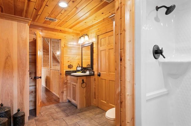 Bathroom featuring wooden walls, vanity, wood ceiling, a shower, and toilet | Image 28