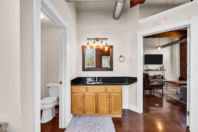 bathroom with baseboards, finished concrete floors, vanity, and toilet | Image 19