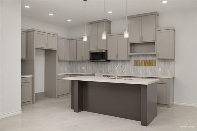 Kitchen with gray cabinetry, a center island with sink, stainless steel microwave, tasteful backsplash, and recessed lighting | Image 7