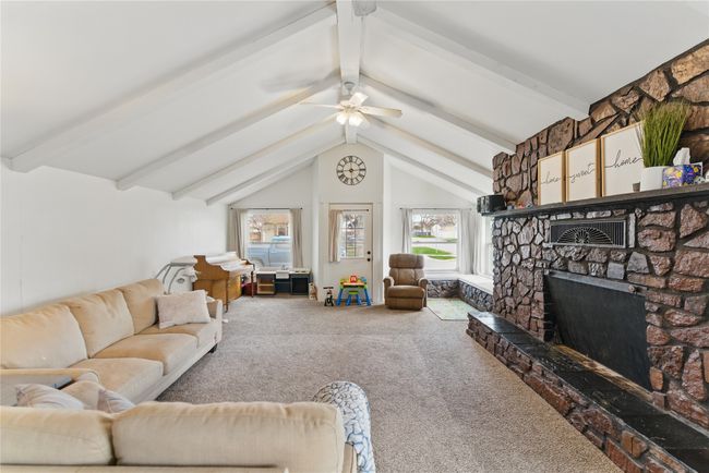 Living area featuring carpet floors, a wealth of natural light, vaulted ceiling with beams, and a stone fireplace | Image 8