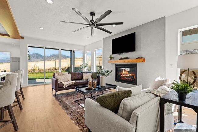 Living area featuring a glass covered fireplace, light wood finished floors, recessed lighting, a ceiling fan, and a textured ceiling | Image 14