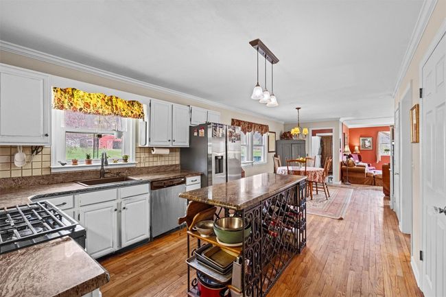 Kitchen with crown molding, tasteful backsplash, light wood-type flooring, appliances with stainless steel finishes, and a sink | Image 6