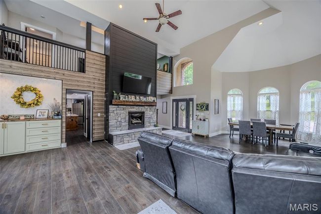 Living room featuring high vaulted ceiling, a stone fireplace, a ceiling fan, dark wood-style floors, and recessed lighting | Image 11