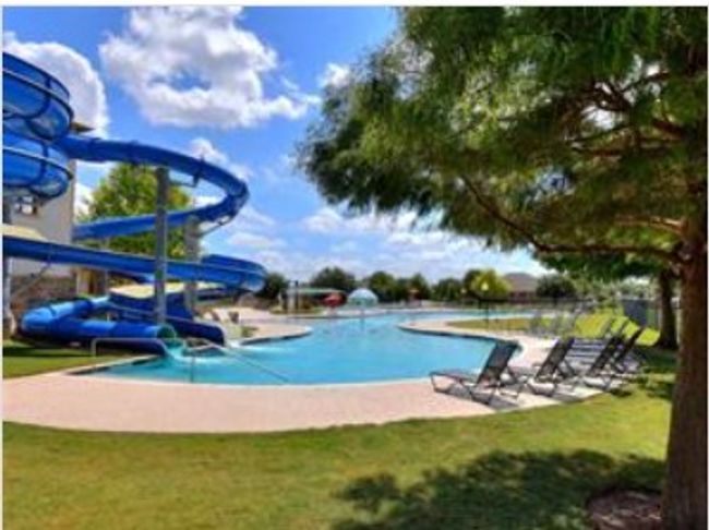 Community pool with a patio, a water slide, and a lawn | Image 33