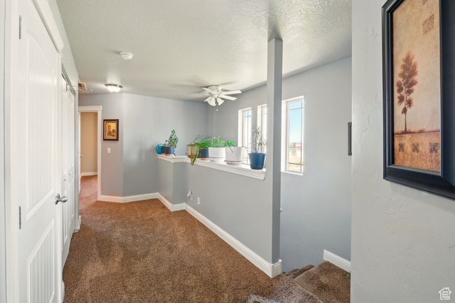 Hallway featuring carpet floors, a textured ceiling, and baseboards | Image 25