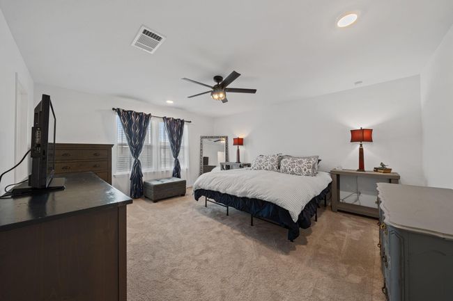Upstairs spacious primary bedroom offers natural light through large windows and features a ceiling fan for added comfort. | Image 25