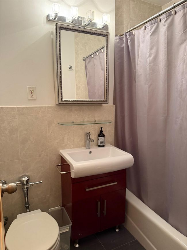 Bathroom with vanity, tile walls, shower / bath combo with shower curtain, tile patterned flooring, and tasteful backsplash | Image 9