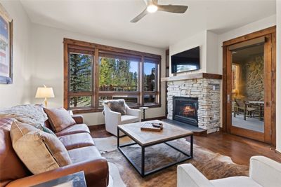 Living room with ceiling fan, a stone fireplace, and dark hardwood / wood-style flooring | Image 2