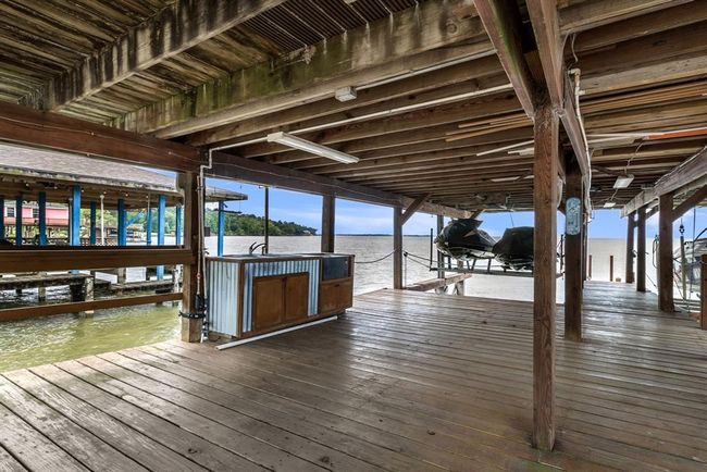 This photo showcases a spacious, covered wooden dock with boat lifts and a scenic waterfront view. Ideal for boating enthusiasts and enjoying lakeside living. | Image 34