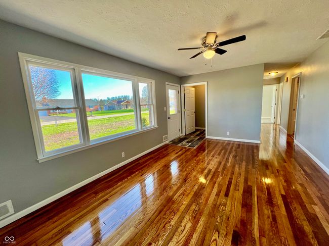 unfurnished living room featuring ceiling fan, baseboards, a textured ceiling, and wood finished floors | Image 5