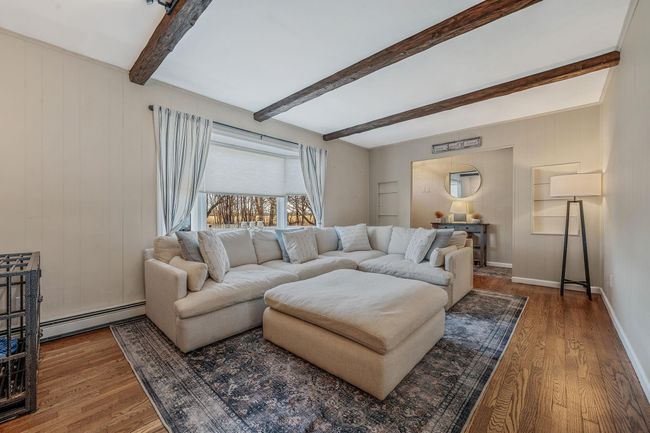 Living room with hardwood / wood-style flooring, a baseboard heating unit, and beamed ceiling | Image 4