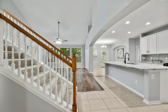 The open-concept kitchen and living areas connect seamlessly, with freshly painted cabinets and an extended island anchoring the space. | Image 7