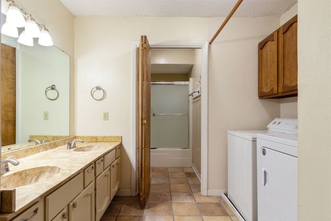 Shared bath featuring double vanity, washer and dryer and storage cabinets | Image 14