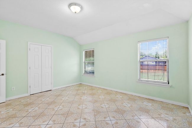Unfurnished bedroom featuring vaulted ceiling, baseboards, light tile patterned floors, and a closet | Image 12