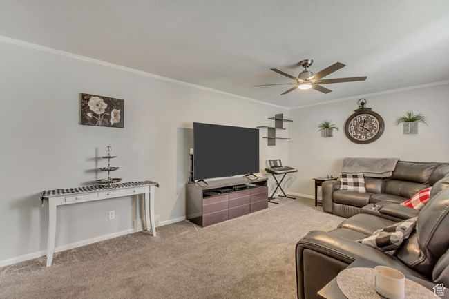 Living room featuring carpet floors, a ceiling fan, baseboards, and ornamental molding | Image 4