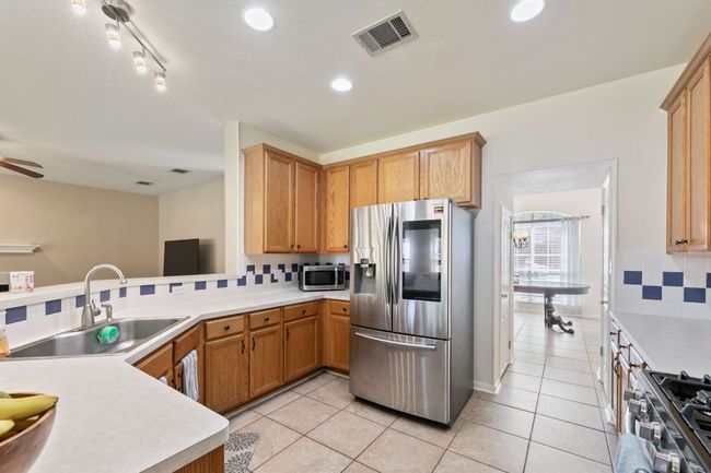 Kitchen featuring appliances with stainless steel finishes, decorative backsplash, light countertops, light tile patterned floors, and recessed lighting | Image 11