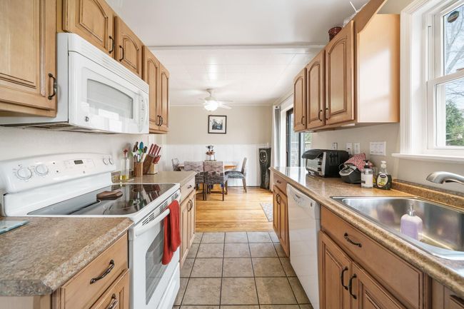 Kitchen with white appliances, a sink, ceiling fan, and a healthy amount of sunlight | Image 13