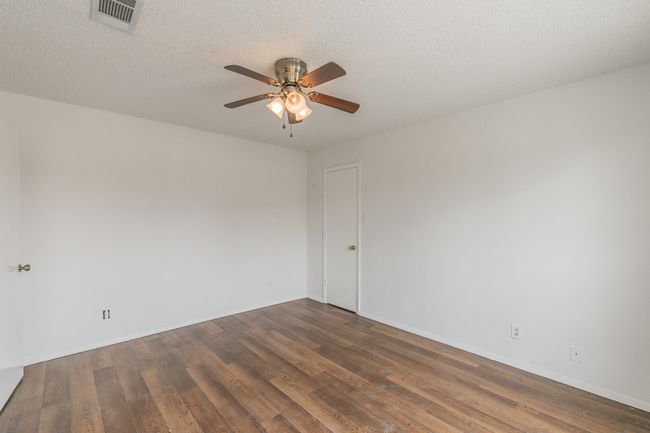 Unfurnished room with a ceiling fan, wood finished floors, baseboards, and a textured ceiling | Image 17